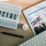 Une configuration de bureau avec les éléments essentiels du marketing sur les réseaux sociaux, notamment un clavier, une lightbox et un guide.