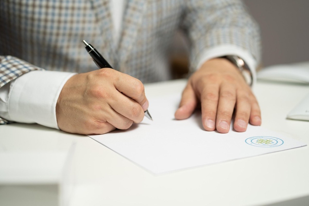 Homme écrivant sur un papier avec un stylo sur une table