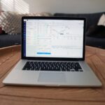 Laptop sur table en bois dans un salon avec canapé et coussins