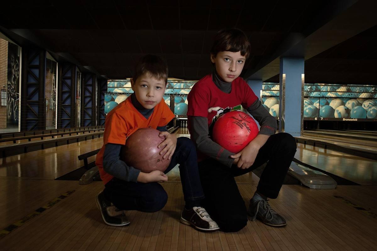 Deux enfants crouchés dans une allée de bowling, tenant leurs boules Deux enfants crouchés dans une allée de bowling, tenant leurs boules