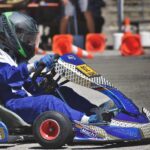 Un pilote en combinaison bleue conduit un kart de course