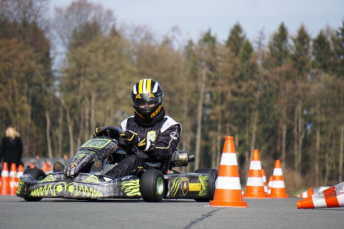 Un pilote en karting navigant entre cônes orange sur piste Un pilote en karting navigant entre cônes orange sur piste