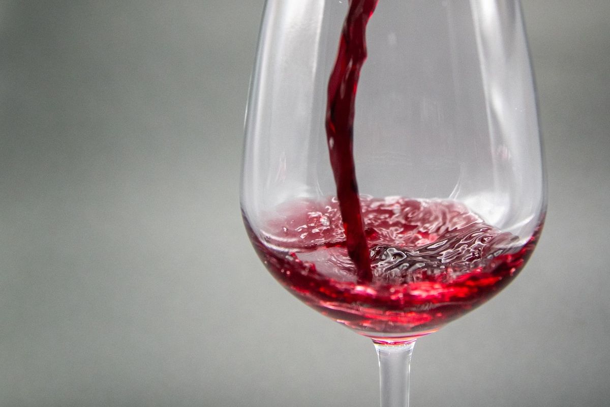 Verre à vin partiellement rempli de vin rouge, bulles en surface, fond neutre Verre à vin partiellement rempli de vin rouge, bulles en surface, fond neutre
